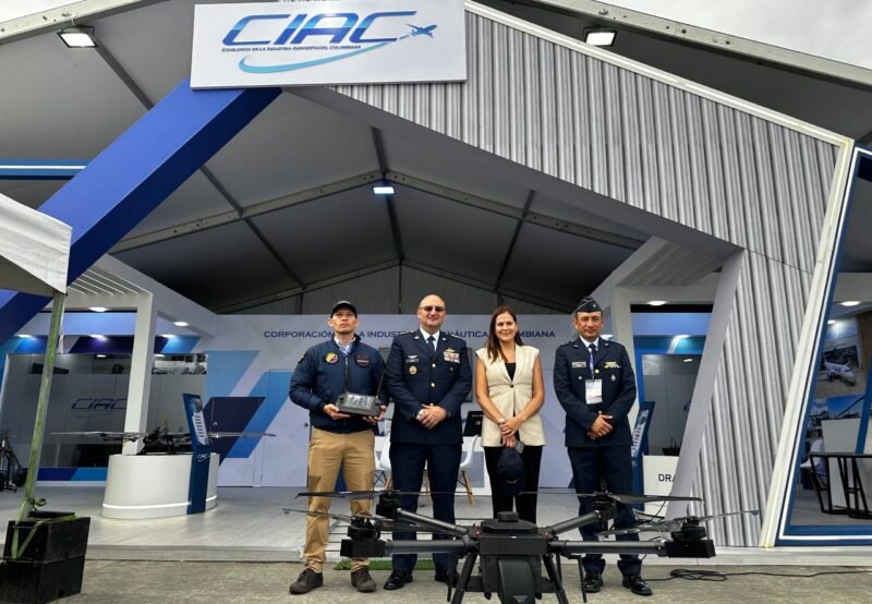 IMG_2910 Cuatro personas (ANDRÉS GÓMEZ INGENIERO CIAC, MG ANDRÉS GUZMÁN PRESIDENTE CIAC, ANA CATALINA CANO, VICEMINISTRA GSED, Y CORONEL TAVERA GERENTE DE DISEÑO Y DESARROLLO CIAC) frente al stand de CIAC en la feria F-AIR 2025, delante de ellos el DRAGOM en el suelo